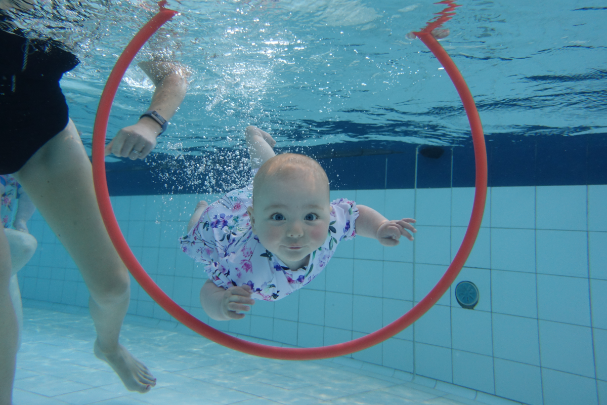 Baby swimming through a hoop underwater